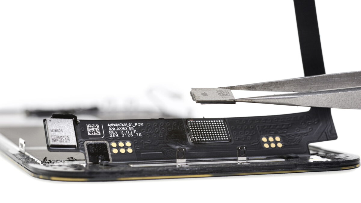 Retirar el chip central de una pantalla del iPhone 13.